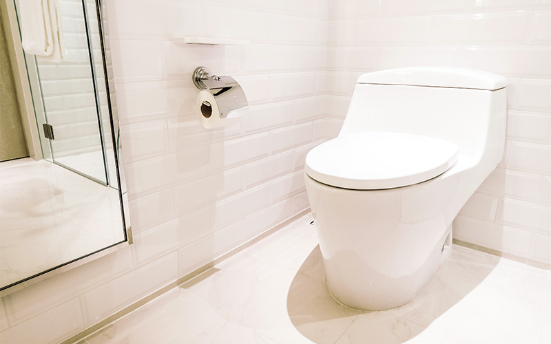 Minimalist bathroom with white toilet, subway tiles, and marble floor.