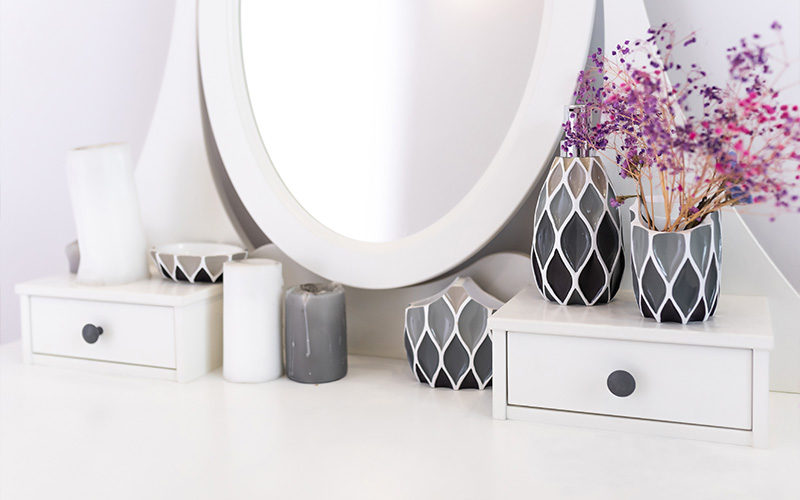 A clean, streak-free mirror on a white vanity table with decorative accessories.