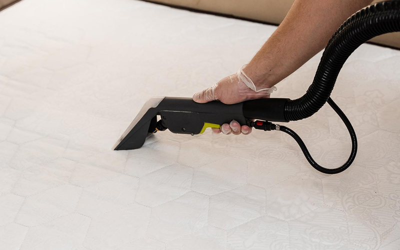 Professional technician deep cleaning a mattress using a vacuum
