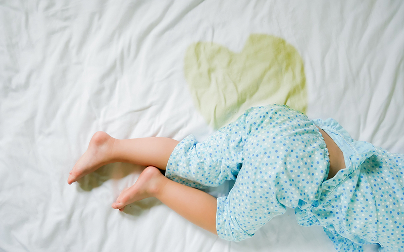 Toddler sleeping next to a urine stain on a mattress