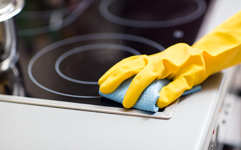 Yellow gloves clean black glass stovetop